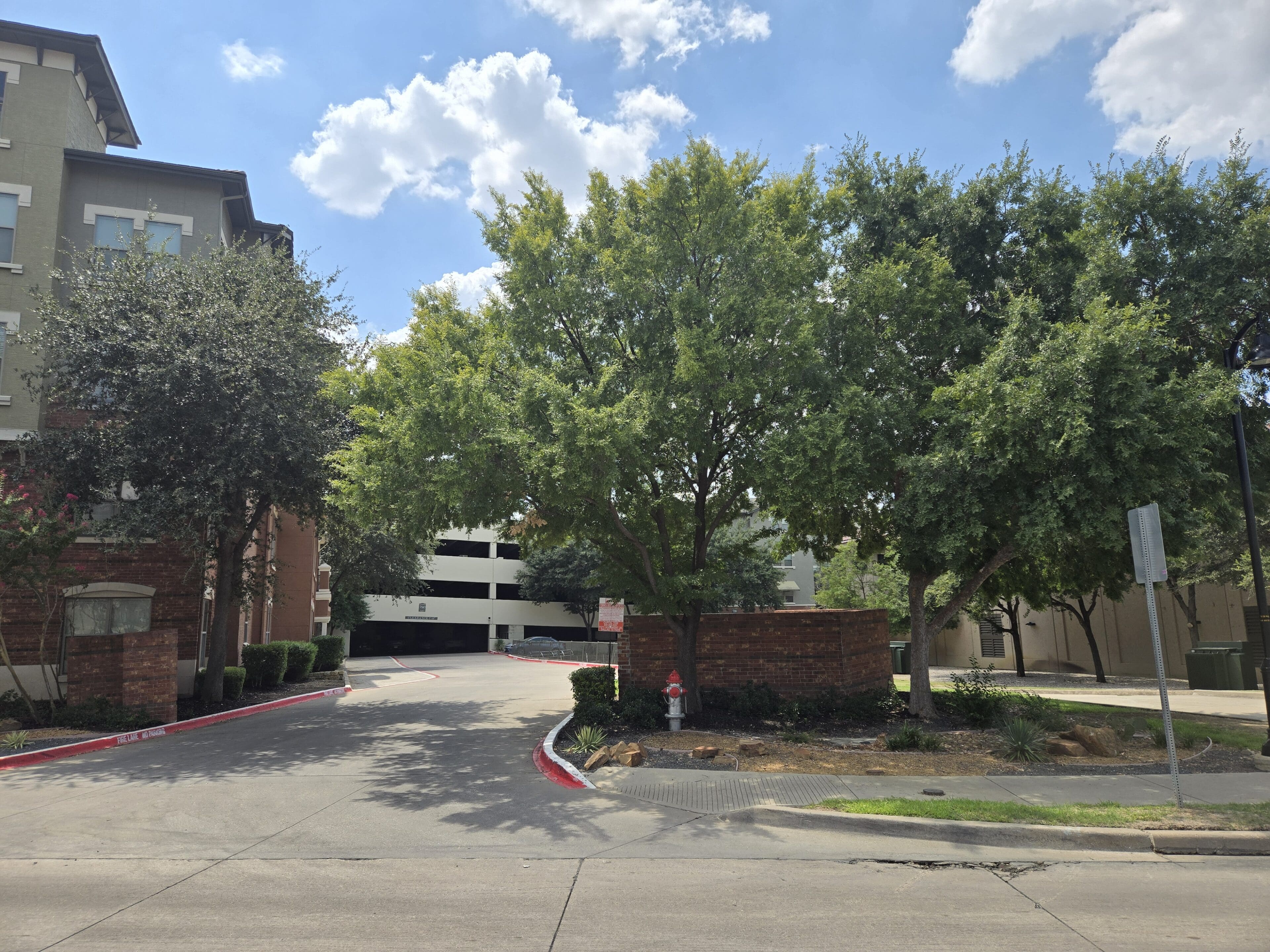 A parking lot with trees and buildings in the background.